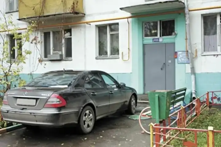 Припаркованный у подъезда автомобиль.