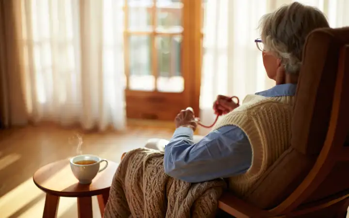 Пожилая женщина смотрит в окно.