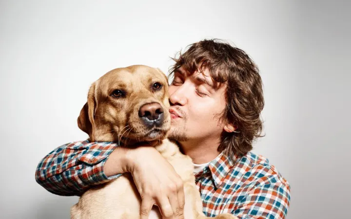 Хозяин обнимает собаку.